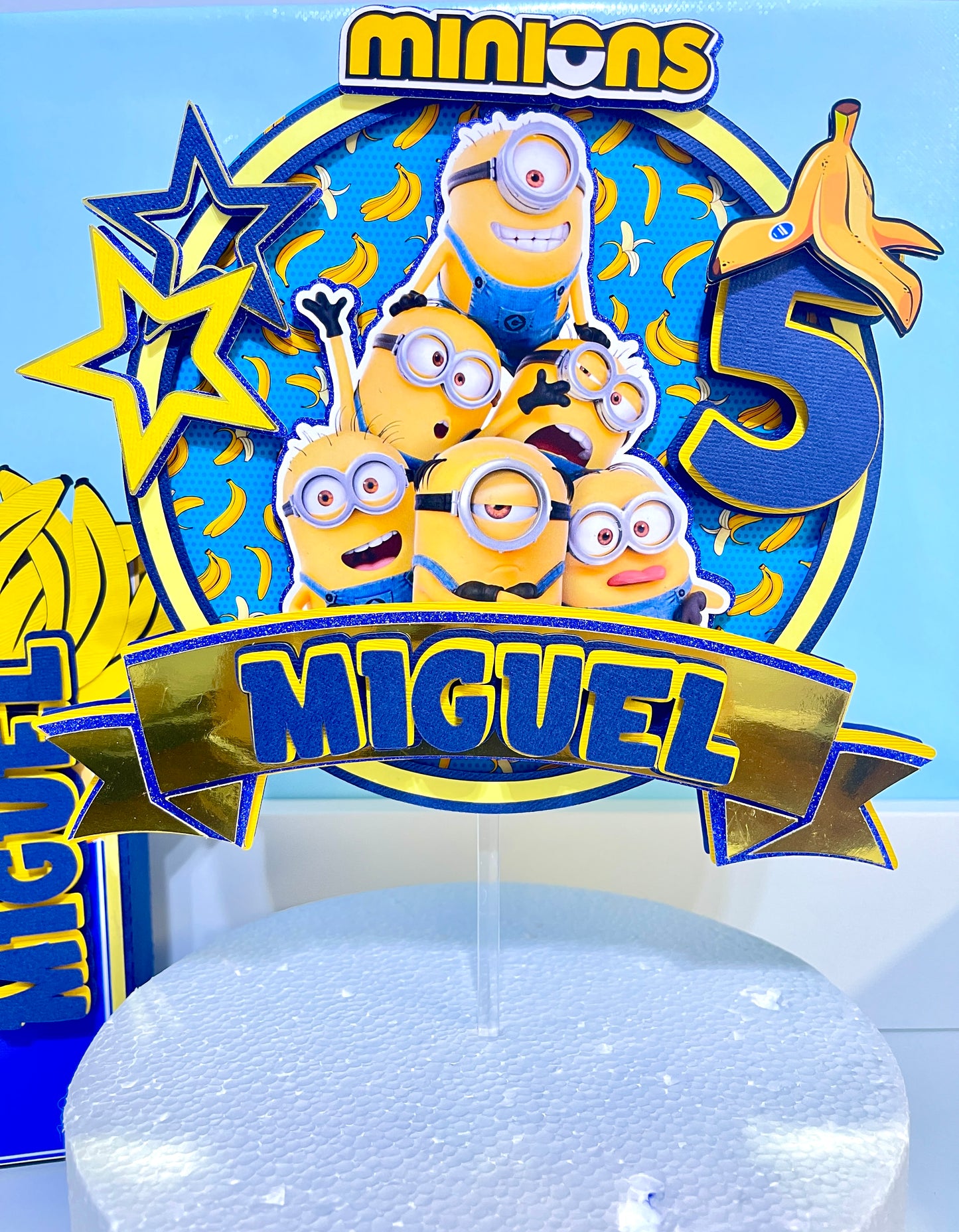 Custom Minions-themed cake topper featuring vibrant colors and intricate designs, perfect for adding a fun touch to birthday celebrations. Made from high-quality cardstock and carefully hand-assembled for precision and detail.